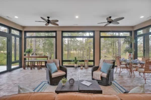 Airy sunroom with wicker furniture, large windows, and wooded views for relaxing and dining.