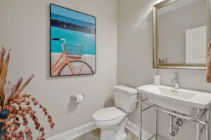 Modern minimalist bathroom with beige walls, white fixtures, and colorful artwork for a warm contemporary look.