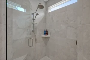 Modern light gray walk-in shower with marble tiles, glass door, and rainfall showerhead.