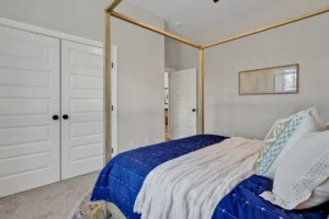 Modern bedroom with blue bedding, gold canopy bed frame, and light gray walls.