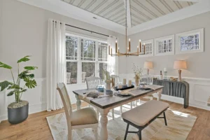 Modern dining room with neutral palette, gold chandelier, wood table, and natural light.