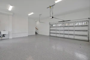 Clean modern garage with polished concrete floor, white walls, utility sink, and frosted window door.