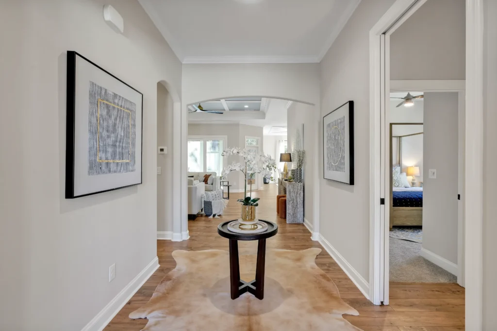 Bright elegant hallway with wood flooring, orchid centerpiece, and view into a sunlit living room.