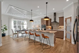 Modern open-concept kitchen with warm wood cabinetry, caramel stools, and natural light.