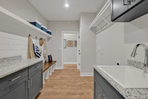 Bright modern farmhouse laundry and mudroom with gray cabinets, wood flooring, and built-in bench.