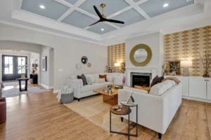 Elegant modern living room with blue coffered ceiling, gray sofas, fireplace, and warm wood flooring.