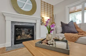 Modern cozy living room with fireplace, gold mirror, beige sofa, and warm natural lighting.