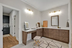 Modern master bathroom with dual vanity, wood cabinetry, makeup area, and warm ambient lighting.