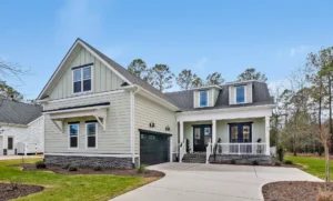 Modern farmhouse exterior with gray siding, black garage door, and white trim in suburban setting.
