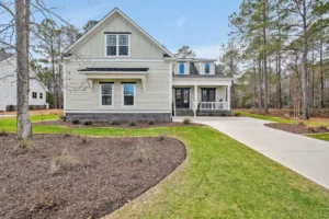 Modern farmhouse with brick accents, dark trim, and pine trees in a peaceful suburban setting.