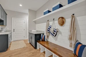 Coastal mudroom with wooden bench, striped pillows, shiplap walls, and organized beach-style storage.