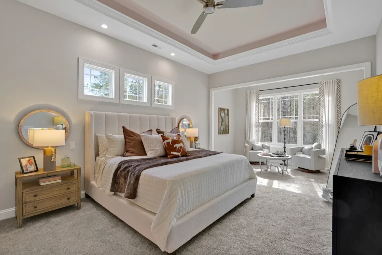 Elegant modern bedroom with tufted headboard, cozy sitting area, and warm neutral luxury décor.