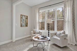 Bright cozy sitting area with white chairs, large window, and elegant natural light.