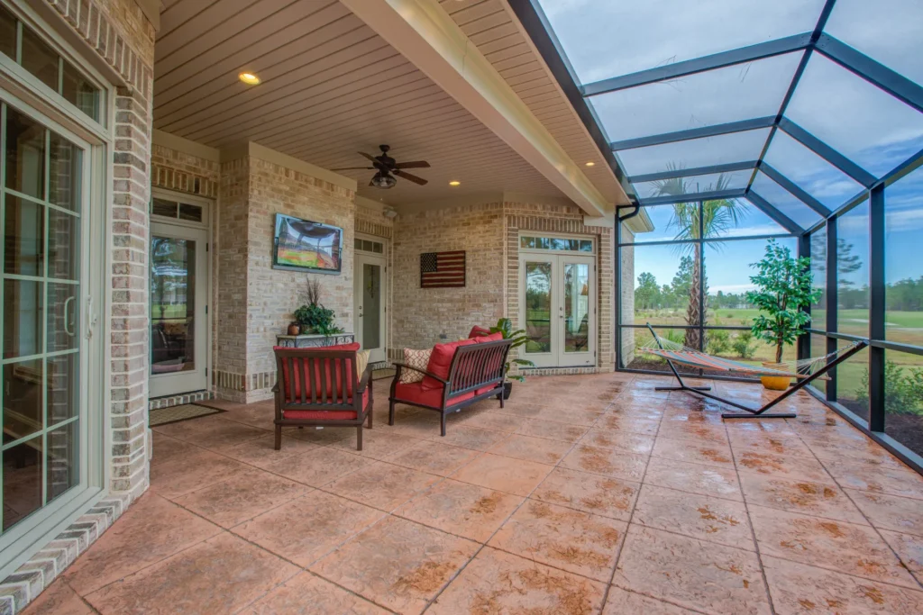 Spacious enclosed patio with glass walls, red seating, and modern outdoor living design.