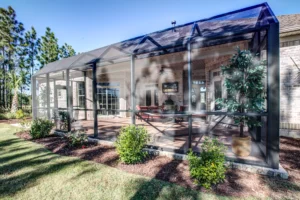 Modern screened patio with elegant seating, black mesh enclosure, and lush landscaped surroundings.