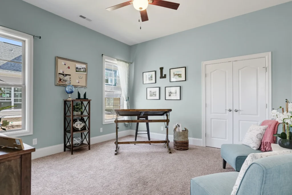 Cozy light blue home office with wooden desk, natural light, and inviting decor.
