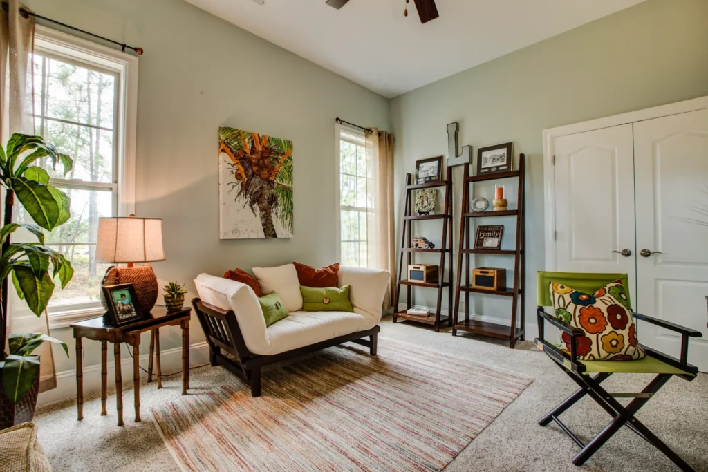 Cozy earth-toned living room with natural light, green walls, white loveseat, and modern decor.