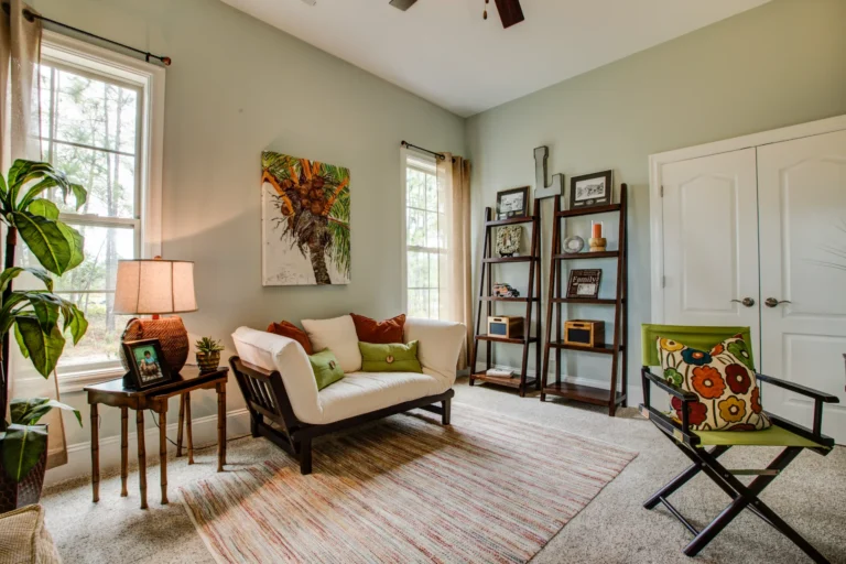 Cozy earth-toned living room with natural light, green walls, white loveseat, and modern decor.