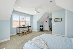 Bright attic bedroom with light blue walls, wooden desk, and cozy natural light.