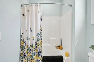 Modern blue bathroom with white tub, floral shower curtain, and bright natural light.