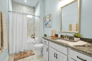 Elegant blue and white bathroom with marble tiles, gold-framed mirror, and granite countertop.