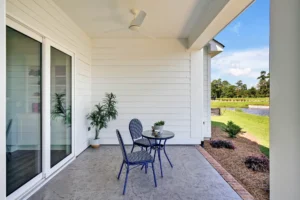 Modern patio with lake view, minimalist seating, concrete floor, and lush green landscape.