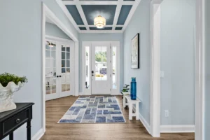 Bright modern coastal entryway with light blue walls, wood floors, and elegant minimalist decor.