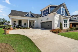 Modern blue and white suburban farmhouse with double garage, front porch, and manicured lawn.