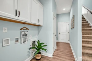Bright modern hallway with blue walls, wood floors, white trim, and cozy coastal decor