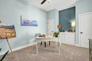 Coastal blue home office with white vintage desk, art easel, and serene creative decor.