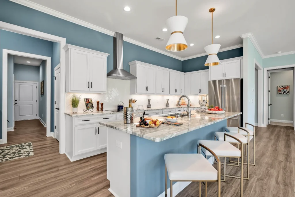 Modern blue and white kitchen with granite island, gold accents, and stainless steel appliances.