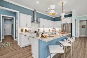 Modern blue and white kitchen with granite island, gold accents, and stainless steel appliances.