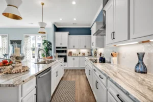 Bright modern white kitchen with marble island, blue accent wall, and gold pendant lighting.