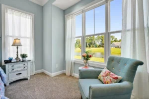 Pastel blue reading nook with sunlight, floral accents, and a relaxing coastal-inspired view.