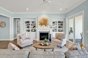 Bright coastal living room with white fireplace, blue walls, and elegant neutral modern decor.