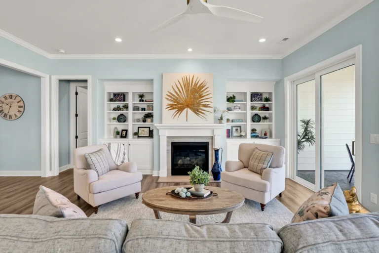 Bright coastal living room with white fireplace, blue walls, and elegant neutral modern decor.