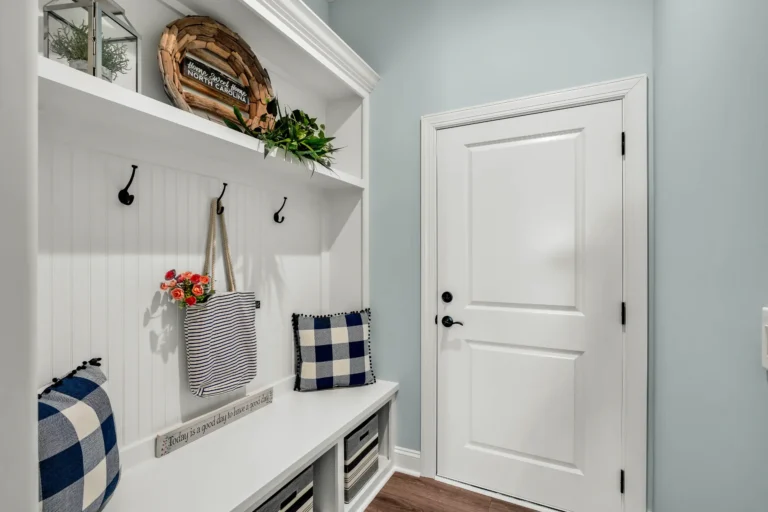 Farmhouse mudroom with white bench, woven baskets, and pastel blue walls.
