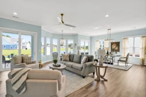 Bright coastal living and dining room with natural light, light blue walls, and modern neutral décor.