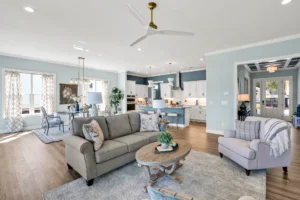 Bright coastal open-concept living room and kitchen with blue island and gray sofa.
