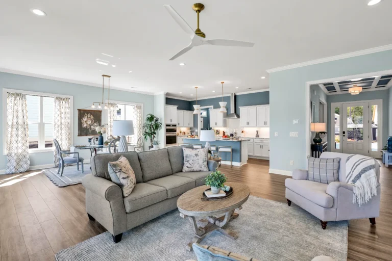 Bright coastal open-concept living room and kitchen with blue island and gray sofa.