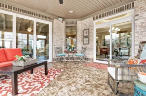 Cozy enclosed patio with brick walls, coral seating, patterned tiles, and warm indoor-outdoor lighting.