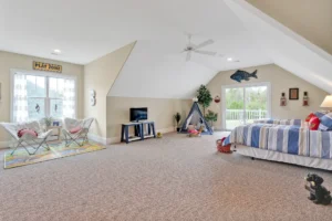 Bright attic bedroom with cozy bed, play tent, butterfly chairs, and natural sunlight.
