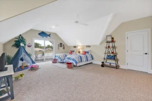Bright coastal kids attic bedroom with twin beds, blue teepee, and sunny play area.