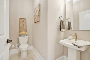 Elegant modern minimalist bathroom with beige walls, white fixtures, and a gold faucet.