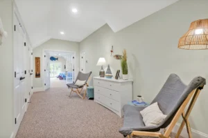 Coastal hallway with light green walls, white trim, cozy seating, and elegant cottage-style decor.