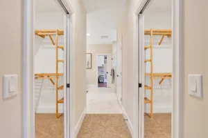 Modern hallway with mirrored closets and beige walls leading to a bright, open living space.