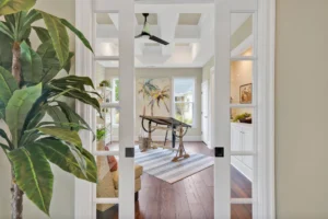 Bright home office with glass doors, rustic wooden desk, coffered ceiling, and modern decor.