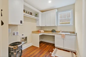Bright modern laundry room with white cabinets, granite countertop, and natural light.