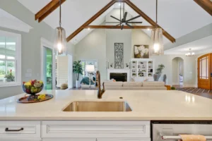 Modern open-concept kitchen and living room with white island, vaulted ceilings, and cozy fireplace.