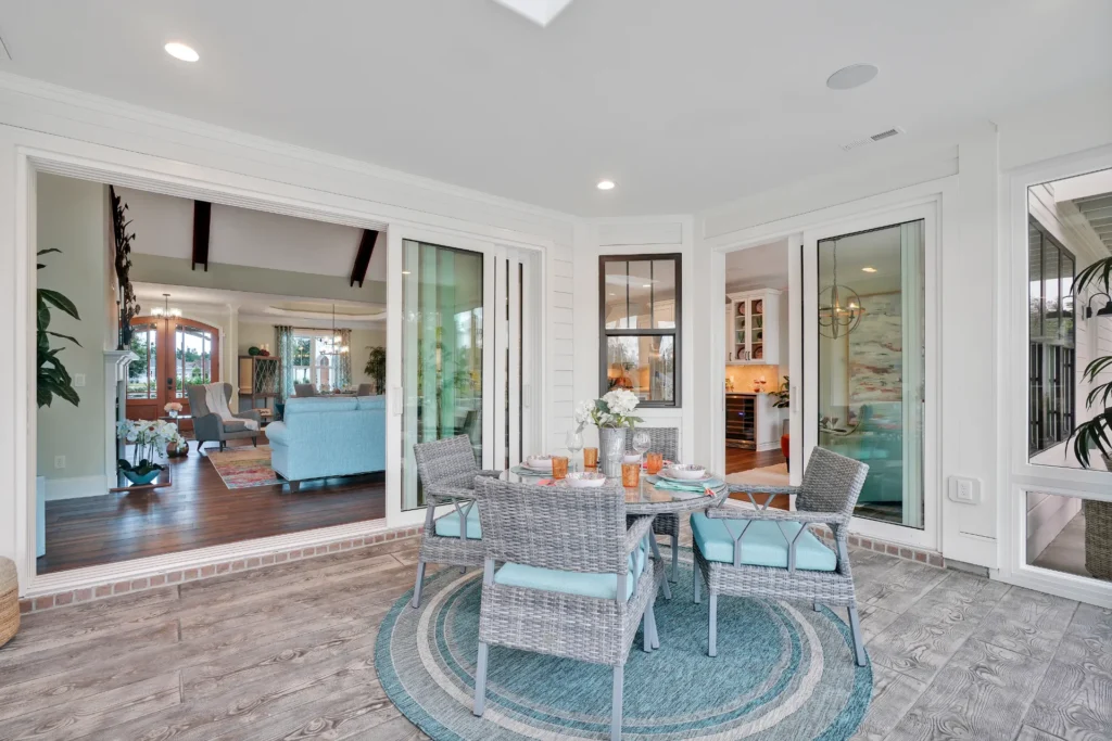 Let Us Reintroduce Ourselves 20 Bright indoor-outdoor living room with wicker patio furniture, light blue accents, and natural wood tones.